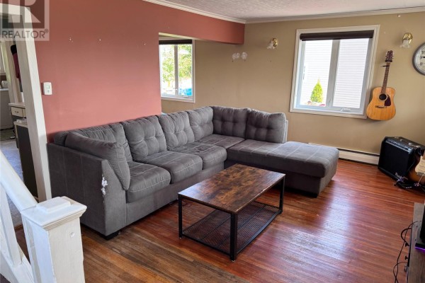 Living room with a grey sectional sofa, coffee table, and hardwood floors. - 122 Lincoln Road, Grand Falls Windsor