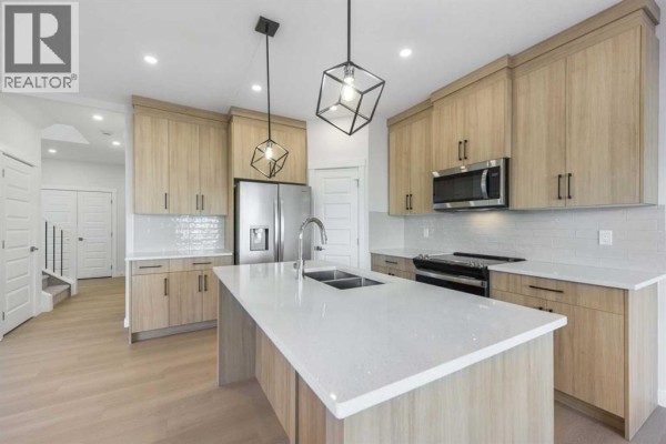 Close-up of kitchen appliances including refrigerator and stove with tile backsplash - 122 Sandpiper Bend, Chestermere