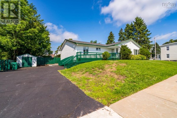 Side view of the white bungalow showing the driveway, shed, and surrounding green trees. - 122 Victoria Street, Windsor