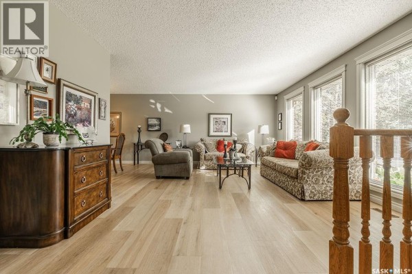 Spacious living area with sofas, coffee table, and large windows overlooking the yard. - 122 Wakaw Crescent, Saskatoon