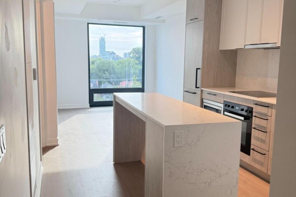 Bright kitchen with white cabinets, wood accents, and a large island with a city view. - 1220 - 89 Montclair Avenue, Toronto