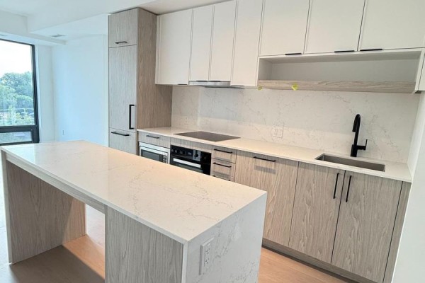 Contemporary kitchen with a large island, white and wood cabinets, and a black faucet. - 1220 - 89 Montclair Avenue, Toronto