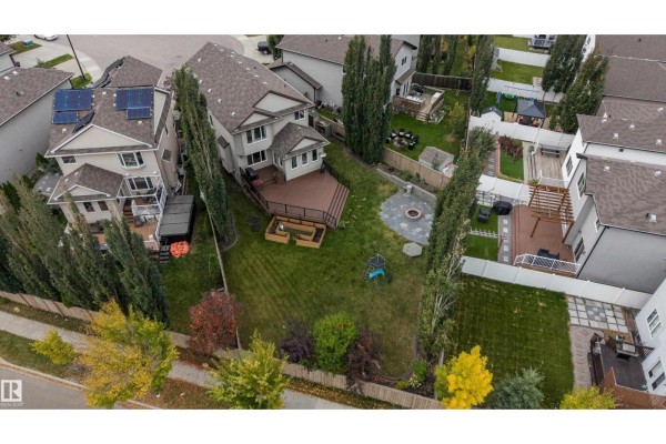 Aerial view of a large backyard with a wooden deck, fire pit, and mature trees. - 12207 171 Av Nw, Edmonton