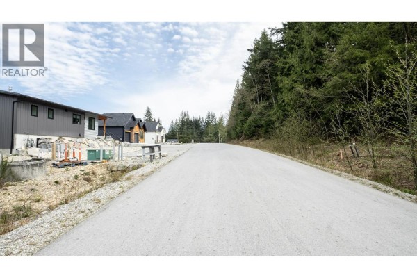 Under-construction homes and natural landscaping are visible from a street corner. - 1221 Castle Road, Gibsons