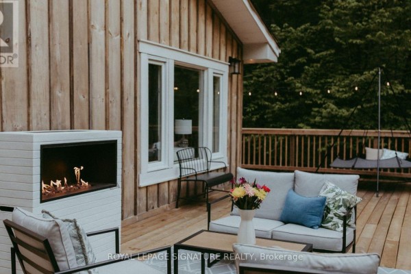 Wooden deck with outdoor furniture, gas fireplace, and house windows. - 1221 Hand Drive, Highlands East
