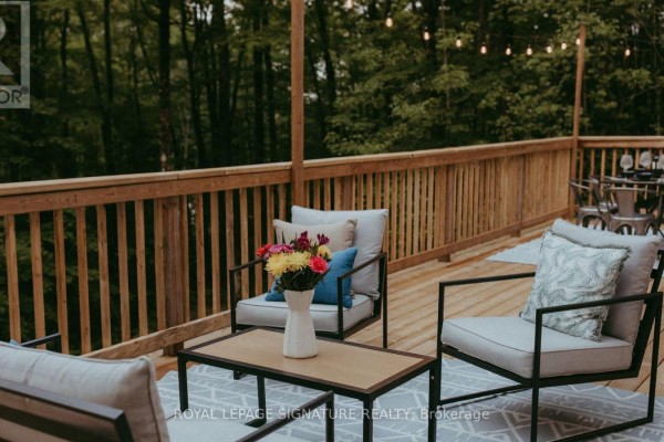 Outdoor seating area on a wooden deck with a coffee table and chairs. - 1221 Hand Drive, Highlands East