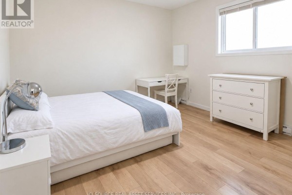 Bedroom with a white queen bed, bedside table, desk, dresser, and light wood flooring. - 1221 Meadowlands Drive E, Ottawa