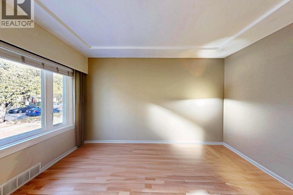 Empty room with light wood floors, beige walls, and a large window with blinds. - 1222 E 51st Avenue, Vancouver