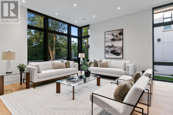 Living room featuring large windows, white sectionals, and modern art on wall. - 1222 Mississauga Road, Mississauga