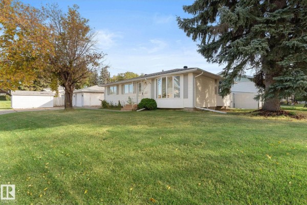 Front view of a white bungalow with a well-maintained lawn and large bay window facing the street. - 12227 58 St Nw, Edmonton