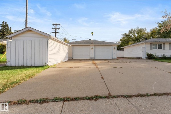 Rear view of the property showing a detached double garage, a single garage, and concrete driveway. - 12227 58 St Nw, Edmonton