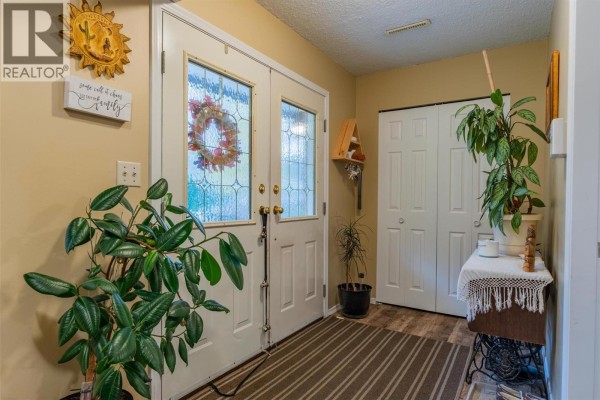 Interior entryway with double doors, plants, a closet, and striped runner rug. - 1224 Third Avenue, Trail