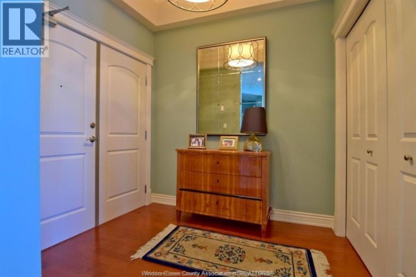 Entryway with light green walls, a wooden dresser, a decorative mirror, and two doors. - 1225 Riverside Dr. Unit# 1204, Windsor