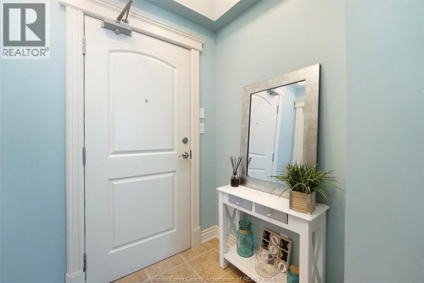 Hallway with white door, console table, mirror, and plant - 1225 Riverside Unit# 409 Windsor