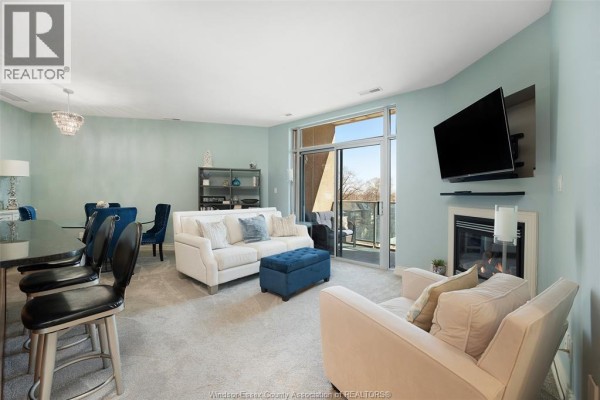 Living room with fireplace, TV, sofa, and balcony access - 1225 Riverside Unit# 409 Windsor