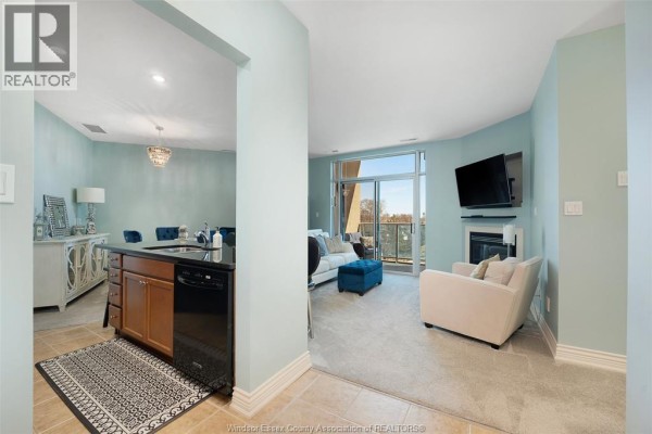 Living room with fireplace, mounted TV, and balcony access - 1225 Riverside Unit# 409 Windsor