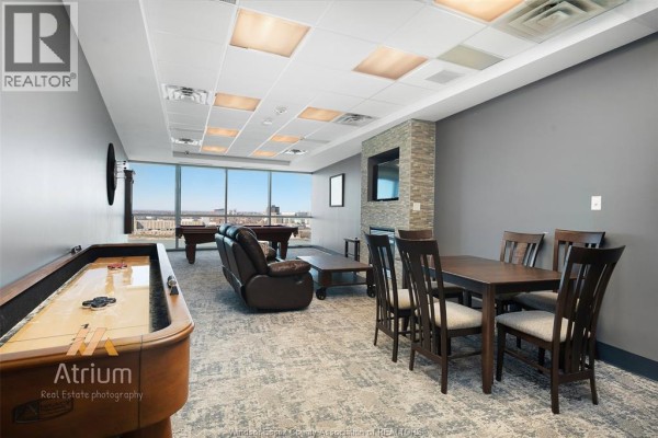 Shuffleboard, pool table, and dining set in a room with large windows - 1225 Riverside Unit# 409 Windsor
