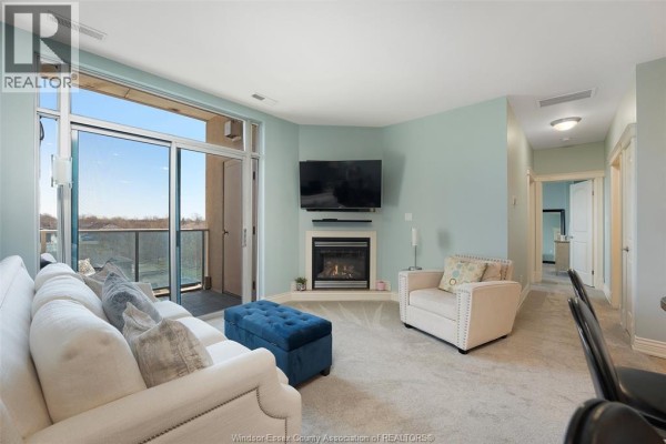 Living room with fireplace, TV, sectional sofa, and balcony access - 1225 Riverside Unit# 409 Windsor