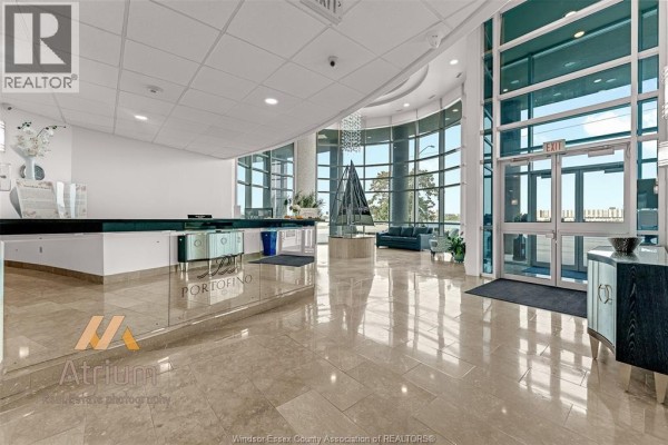 Modern building lobby with reception desk, large windows, and sculpture - 1225 Riverside Unit# 409 Windsor