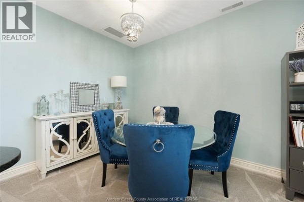 Glass dining table with blue velvet chairs, crystal chandelier, and buffet - 1225 Riverside Unit# 409 Windsor