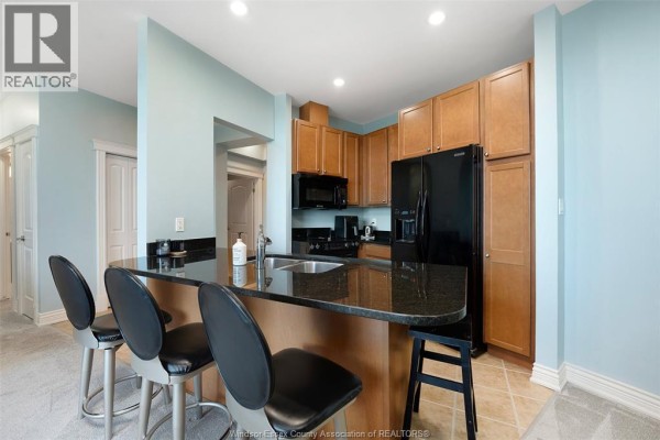 Kitchen with black granite island, black appliances, and breakfast bar - 1225 Riverside Unit# 409 Windsor