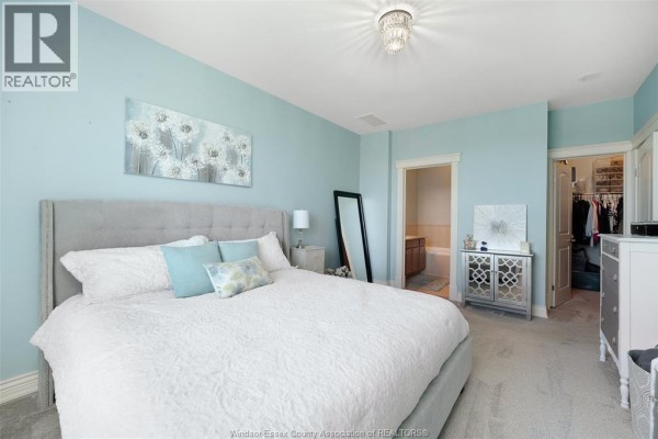 Bedroom with tufted headboard bed, walk-in closet, and ensuite bathroom visible - 1225 Riverside Unit# 409 Windsor