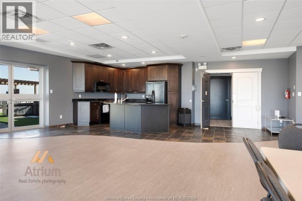 Modern kitchen with dark wood cabinets, island, and double doors - 1225 Riverside Unit# 409 Windsor