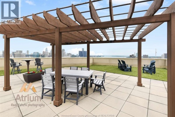 Rooftop patio with pergola, dining table, lounge chairs, city & water view - 1225 Riverside Unit# 409 Windsor