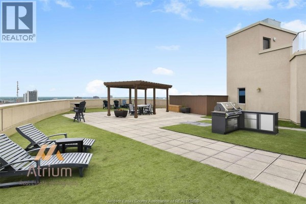 Living room with light blue walls, beige carpet, white sofa, and balcony view - 1225 Riverside Unit# 409, Windsor