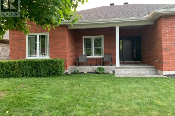 Front entrance of a red brick house with two chairs on the concrete porch and a double black door. - 1228 Innwood Avenue, Cornwall