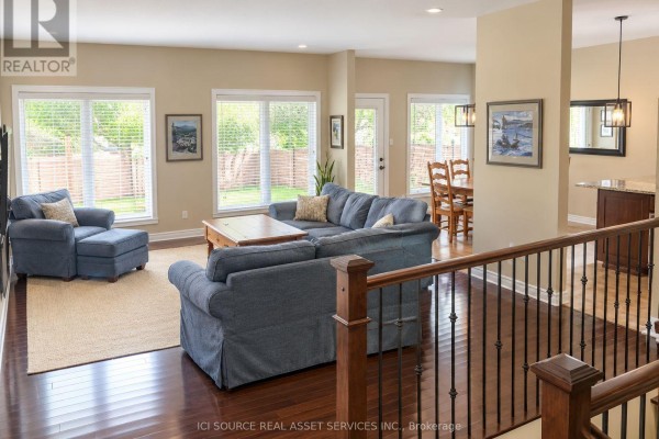 Living room with beige carpet, a wooden banister staircase, and a sliding glass door leading to a balcony. - 1228 Innwood Avenue, Cornwall