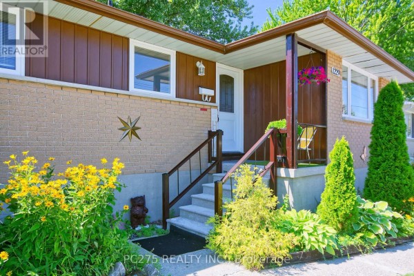 Close-up of the front entrance with steps, railing, porch, and surrounding garden. - 1229 Exmouth Street, Sarnia
