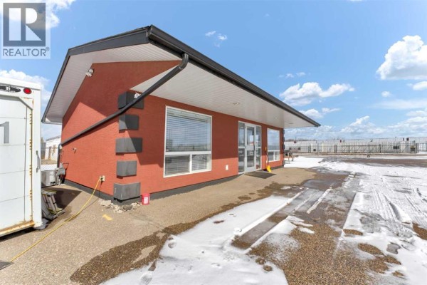 A waiting area with a brown leather sofa, a coffee table, and a view into an office through a doorway. - 1229 South Railway Street Se, Medicine Hat