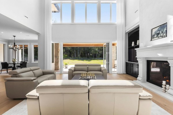 Living room with high ceilings, large windows, leather sofas, and a fireplace. - 123 208 Street, Langley