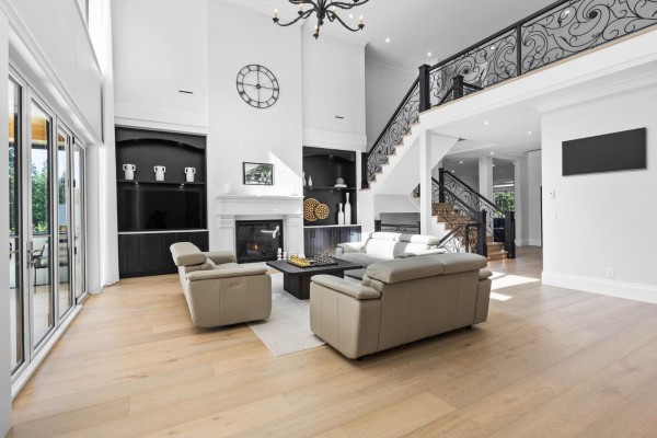 Spacious living room with a fireplace, leather sofas, a grand staircase, and hardwood floors. - 123 208 Street, Langley