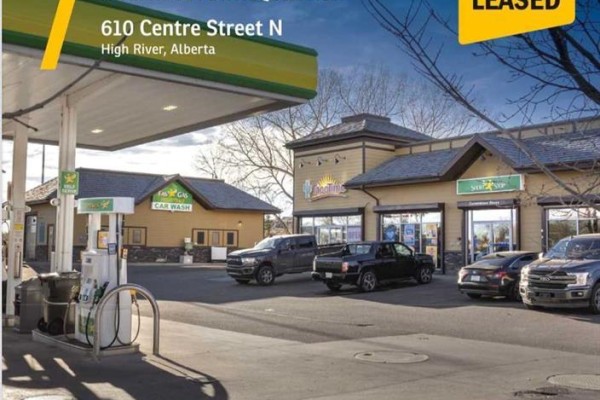 View of gas pumps under a canopy, with various vehicles parked at adjacent businesses. - 123 Any St  N, High River