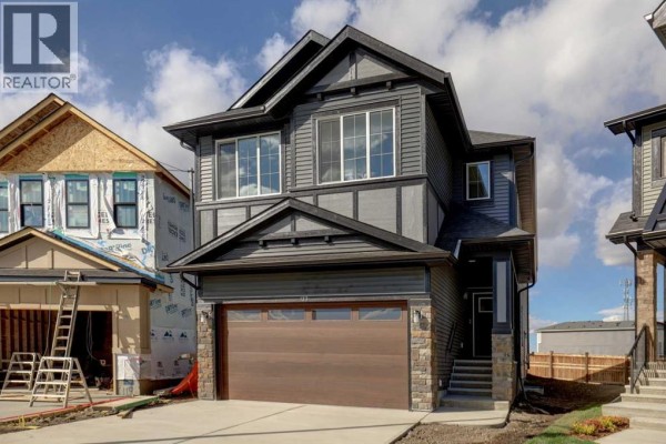 Exterior of a grey and dark grey two-story house with a wood garage door and stone accents. - 123 Homestead Circle Ne, Calgary