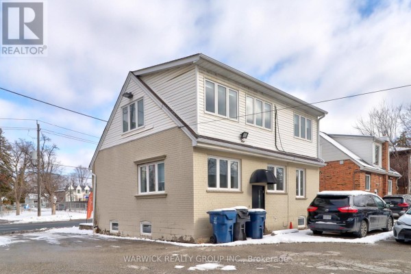 Exterior view of a two-story commercial building with beige brick and siding. - 123 Sheppard Avenue E, Toronto