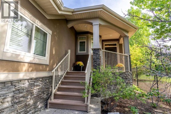 Close-up of the house entrance, showing stone facade, steps, and covered porch. - 123 West Grove Rise Sw, Calgary