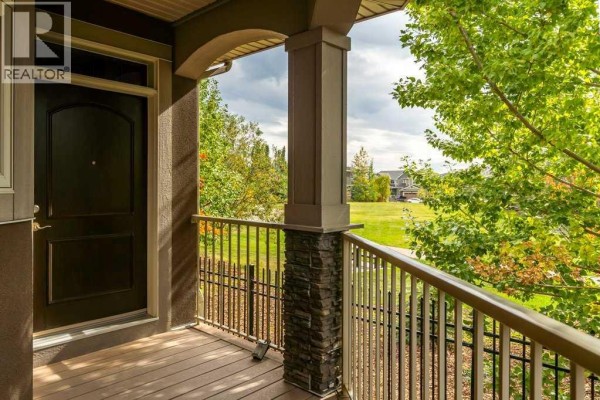 View from the covered porch looking towards the front door and surrounding trees. - 123 West Grove Rise Sw, Calgary