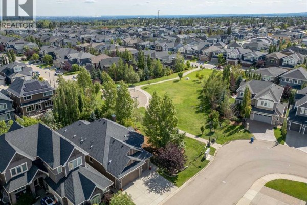 Aerial view of the house with a park and a suburban neighborhood behind it. - 123 West Grove Rise Sw, Calgary