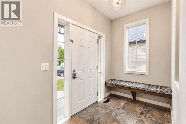 Interior entryway with a white door, side windows, built-in bench, and slate tile flooring. - 123 Wiley Crescent, Red Deer