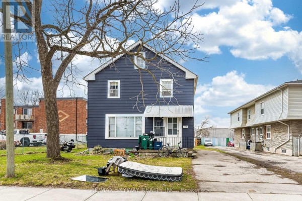 Front view of the blue house with a mattress and debris in the yard. - 1230 Duke Street, Cambridge