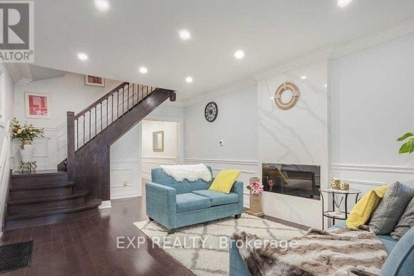 Living room with dark wood floors, a blue sofa, and a modern fireplace. - 1231 Bathurst Street, Toronto