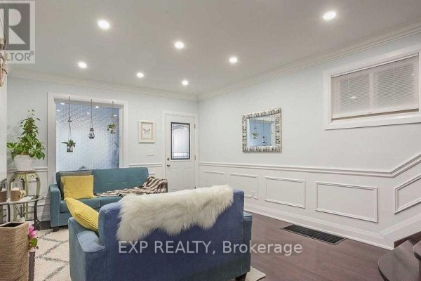 Living room with white wainscoting, a decorative mirror, and a staircase. - 1231 Bathurst Street, Toronto