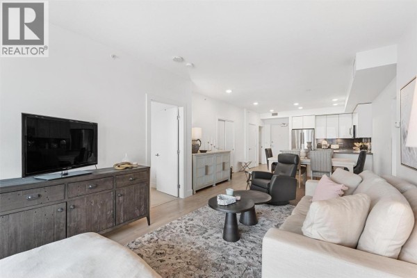 Living room and open concept kitchen with light wood floors and white cabinets. - 1232 Ellis Street Unit# 902, Kelowna