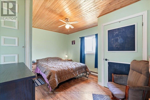Bedroom with wood plank ceiling, ceiling fan, double bed, and chalkboard doors - 1233 Lazier Road Tyendinaga
