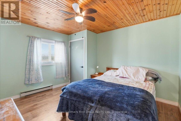 Bedroom with wood paneled ceiling, ceiling fan, bed, and window - 1233 Lazier Road Tyendinaga