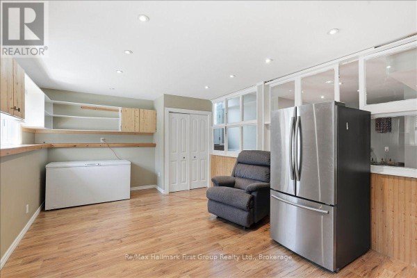 Stainless steel refrigerator and recliner in a room with built-in shelving and wood paneling - 1233 Lazier Road Tyendinaga