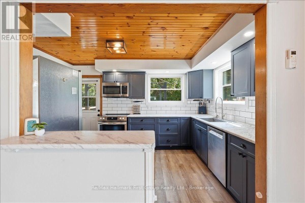 Renovated kitchen with dark blue cabinets, stainless steel appliances, and wood ceiling - 1233 Lazier Road Tyendinaga